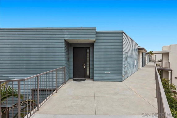 Front view of a modern building with a flat roof and a walkway leading to the entrance.
