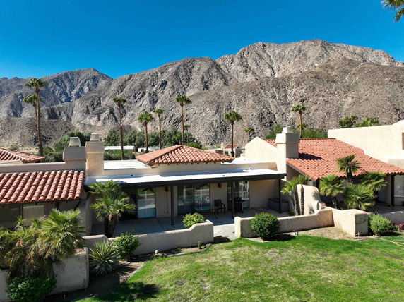 Exterior view of a house with a red-tiled roof and desert mountain backdrop.