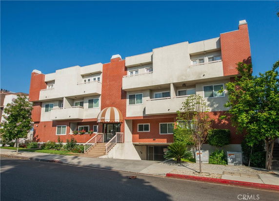 Front view of a three-story apartment building with a mix of brick and stucco exterior.