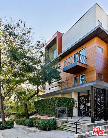 Front view of a modern multi-story building with balconies and a decorative entrance gate.