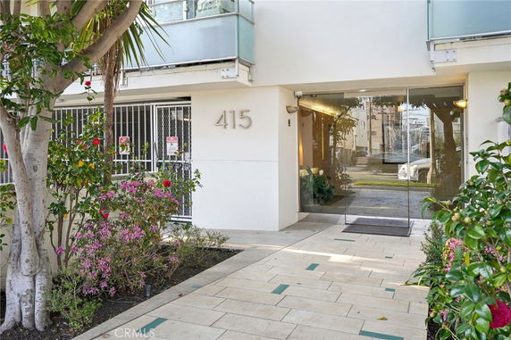Entrance view of a residential building with a glass door and surrounding greenery.
