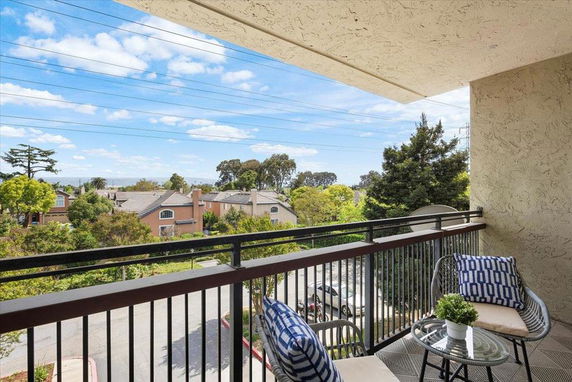 View from a balcony overlooking a residential area with houses and trees.