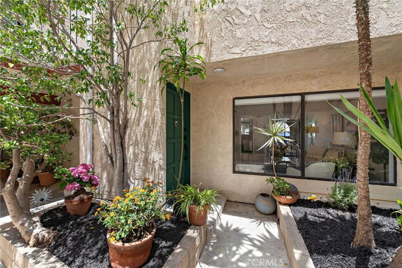 Front view of a house entrance with plants and large window.