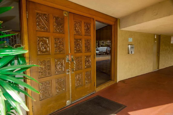 Front view of a building entrance with ornate wooden double doors.