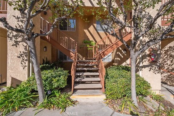 Front view of a building with an exterior staircase and surrounding greenery.