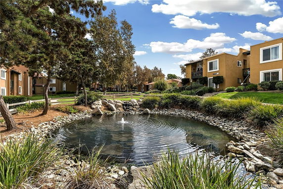 View of residential buildings with a pond and landscaped surroundings.