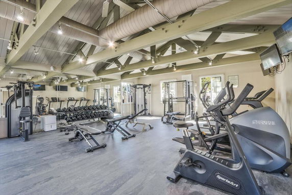 Indoor gym area with exercise equipment and weights.