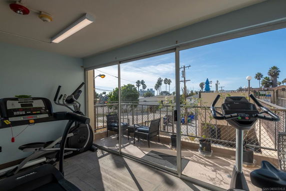 Indoor exercise area with treadmills and a view through glass doors.