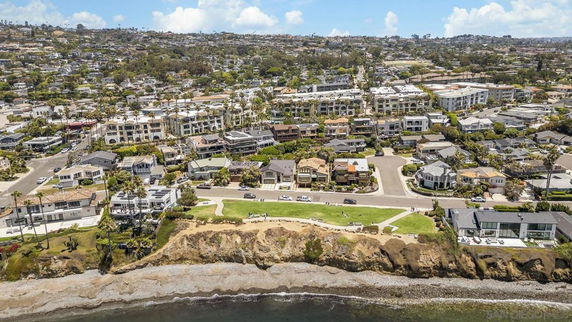 Aerial view of a coastal residential area with houses and cliffs overlooking the ocean.