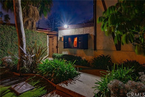 Night view of a building with a spotlight illuminating its exterior and a garden path leading to the entrance.