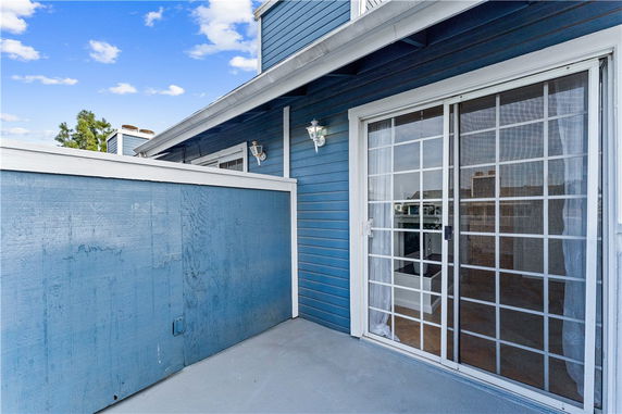 View of a rooftop area with blue siding and sliding glass door.
