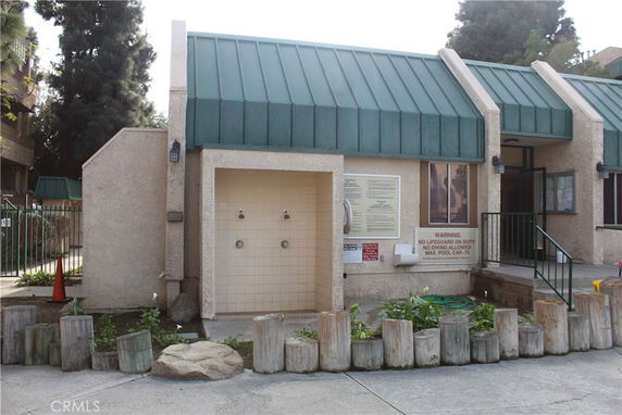 Front view of a building with a tiled outdoor shower area and green awning.