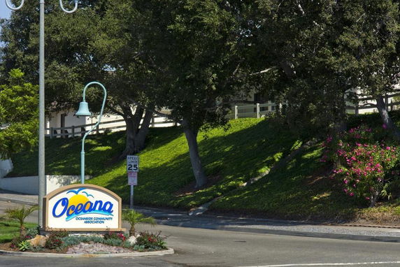Entrance view of Oceana Oceanside Community Association with trees and landscaping.