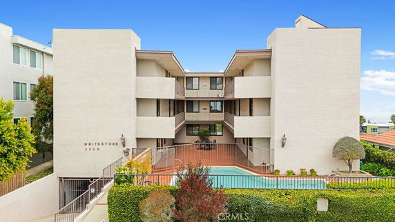 Front view of a multi-story building with balconies and a swimming pool.