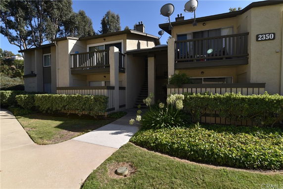 Front view of a multi-unit residential building with balconies and satellite dishes.