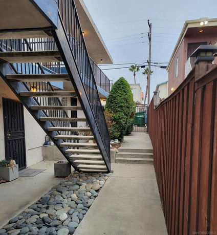 Front view of a building with exterior stairs and a wooden fence.