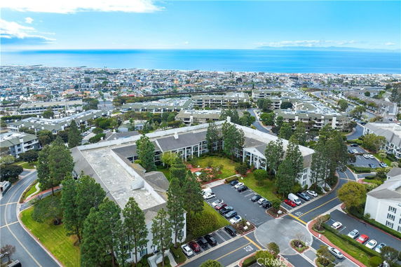 Panoramic view of a residential complex with parking and ocean in the background.