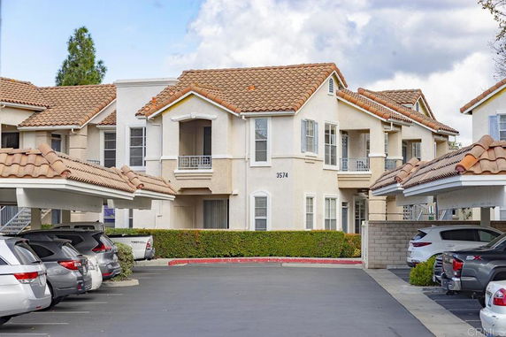 Front view of a house with a tiled roof and attached covered parking area.