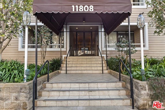 Front view of a building entrance with a canopy and stairs leading up to the door.