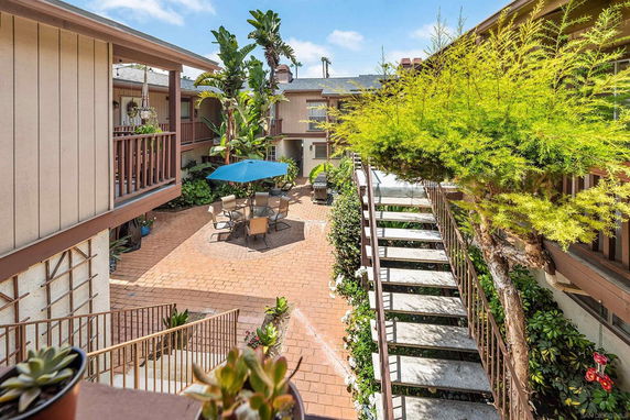 View of a courtyard area with stairs, plants, and outdoor seating.