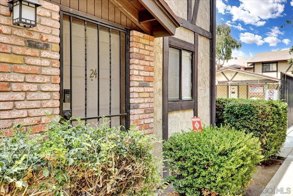 Front view of a house with brick and stucco exterior and numbered door.
