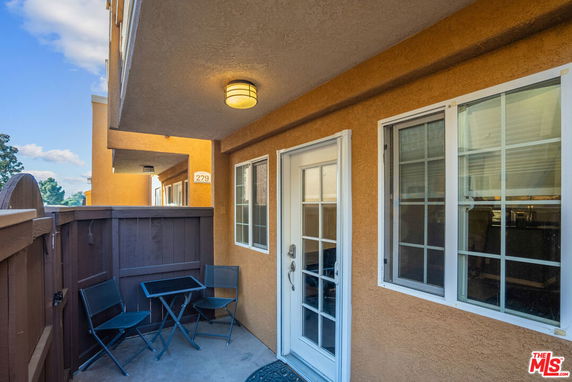 Outdoor patio area with a door and windows, part of a residential building.