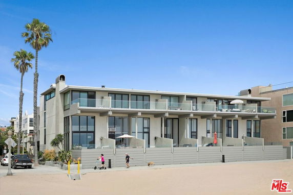 Front view of a modern multi-story building with glass balconies and large windows.