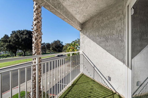 Balcony view with railing and partial view of the street and trees.
