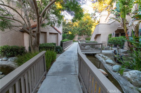Walkway with bridges and plants in an apartment complex courtyard.