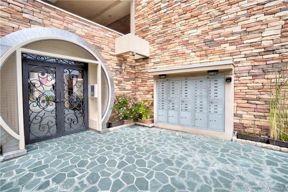 Front view of a building entrance with stone facade and ornate metal doors.