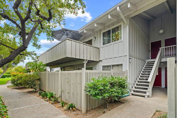 Front view of a two-story apartment building with an external staircase and balcony.