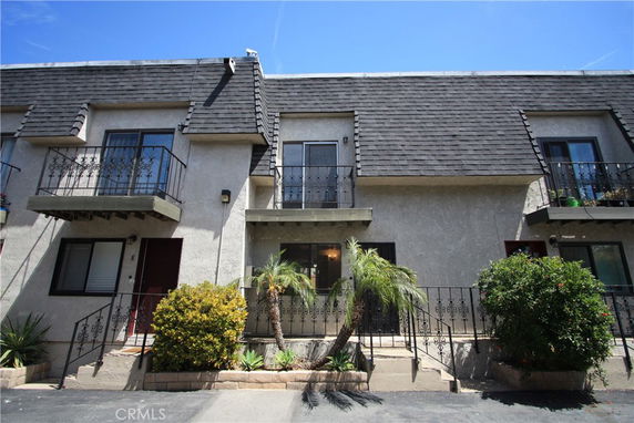 Front view of a multi-story house with balconies and a sloped roof.