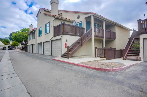 Front view of a two-story building with exterior stairs and multiple garages.