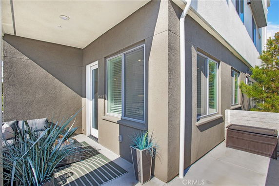 Outdoor corner view of a building with a doorway, windows, and patio furniture.
