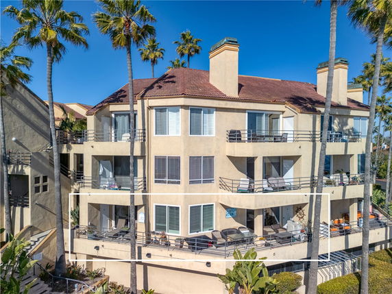 Front view of a multi-story apartment building with balconies and a tiled roof.
