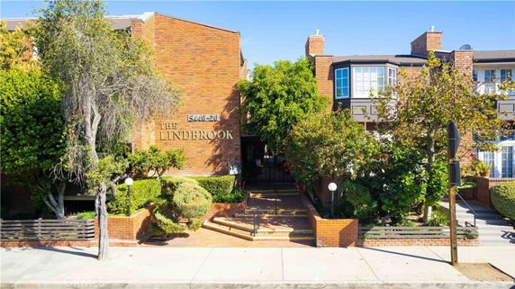 Front view of a brick apartment building with signage and landscaped entrance.