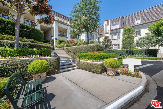 Front view of a multi-story building with manicured landscaping and paved walkway.