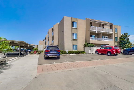 Outdoor parking area in front of a multi-story residential building.