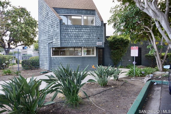 Front view of a two-story house with a unique shingle design and large windows.