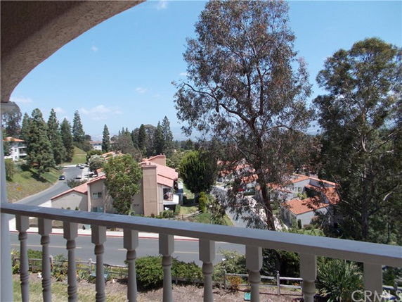 Panoramic view from a balcony overlooking a residential area with houses and trees.