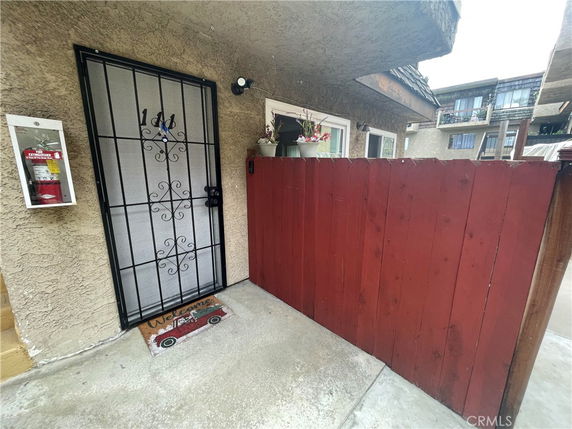 Front view of a building entrance with a metal security door and red wooden fencing.