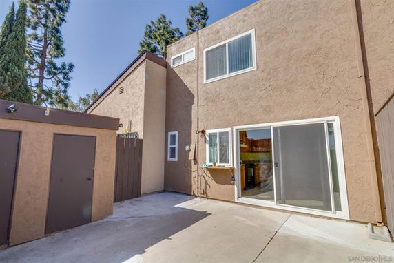Exterior view of a two-story house with sliding glass doors and several windows.