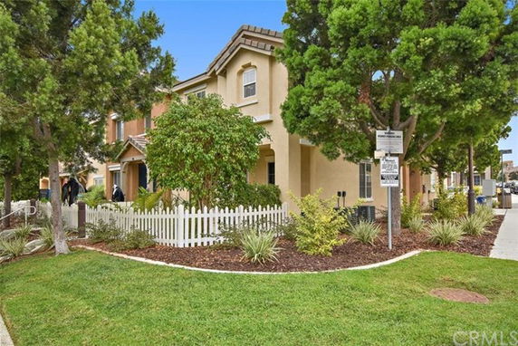 Front view of a two-story house with a white picket fence.