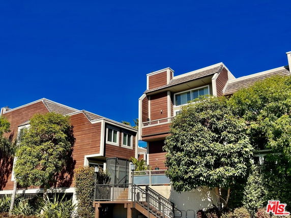 Front view of a multi-story house with wooden siding and large windows.