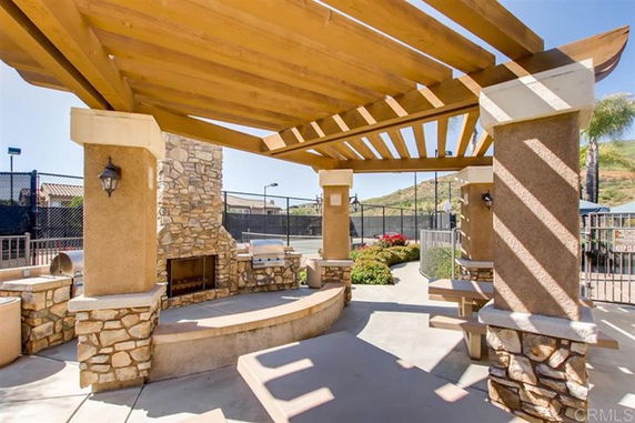 Outdoor club house area with stone fireplace and wooden pergola.