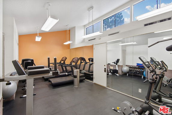 Indoor gym area with exercise equipment and mirrors on the wall.