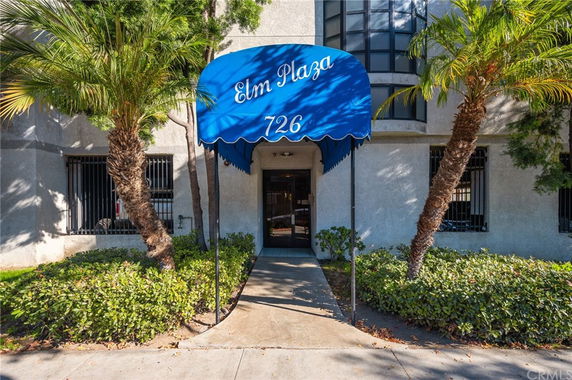 Front view of a building with entryway canopy and palm trees.