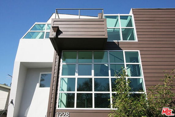 Front view of a modern multi-story building with large windows and a balcony.
