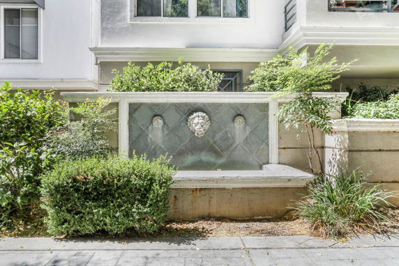 Front view of a building with decorative fountain and plants.