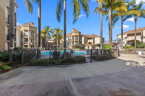 Outdoor view of residential buildings with a central swimming pool surrounded by palm trees.